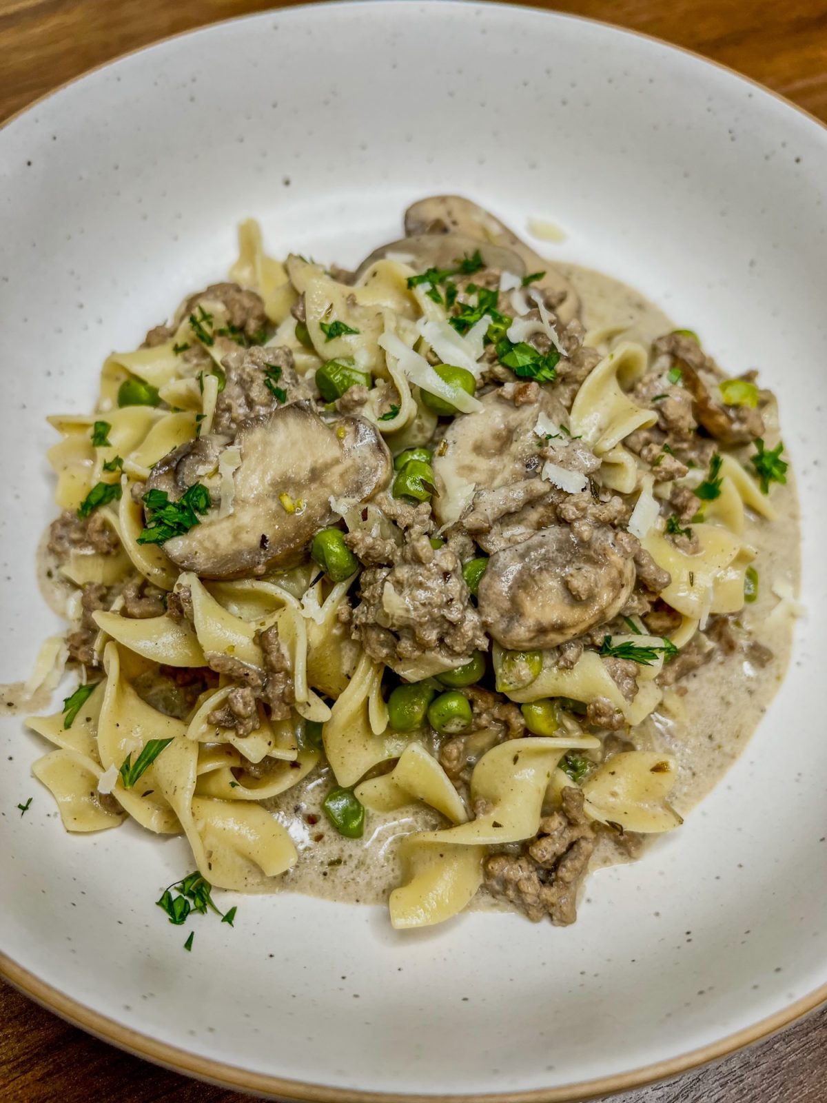 Beef stroganoff in a white bowl on a wooden countertop