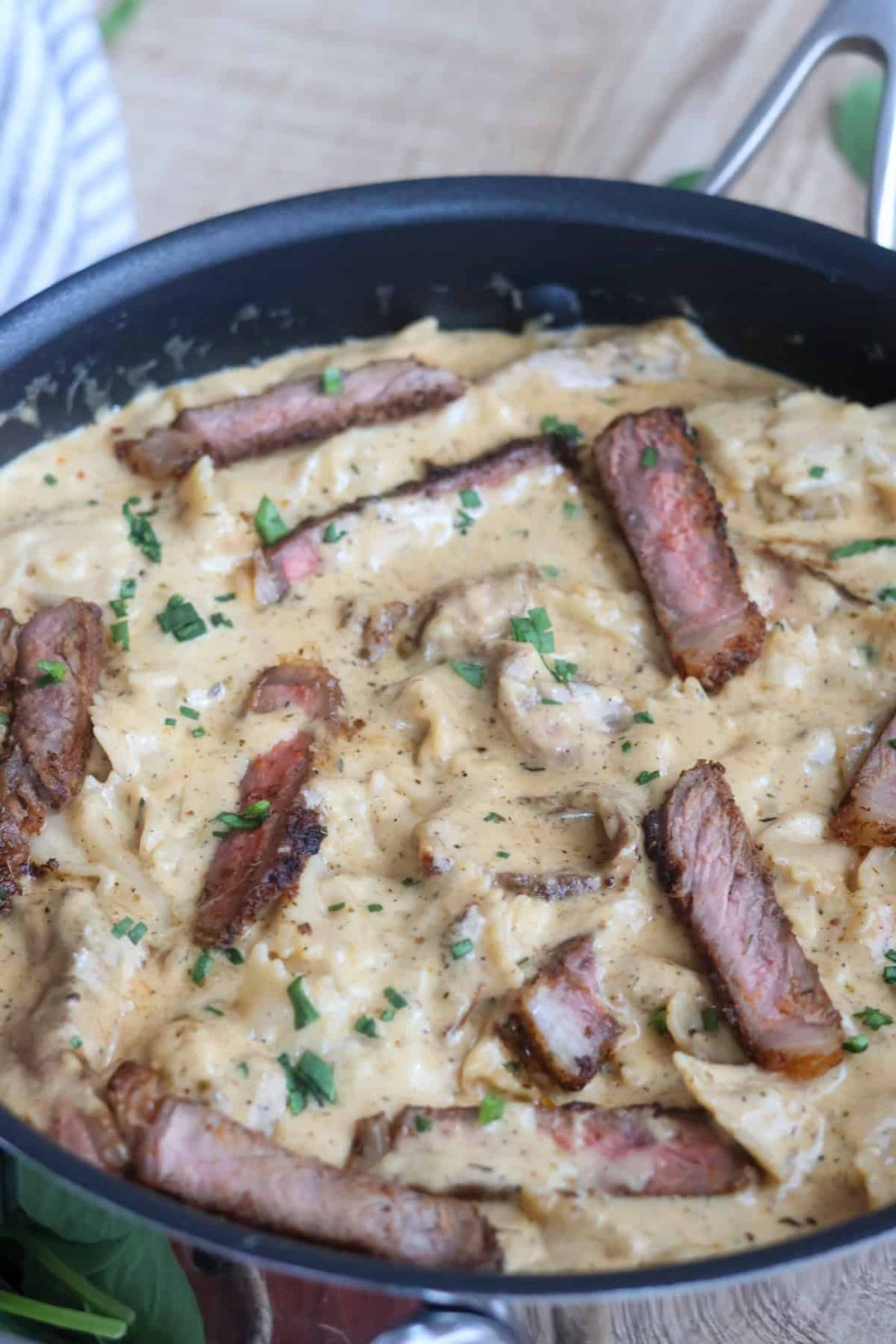 Steak fettuccine Alfredo in a pan with some fresh herbs on top