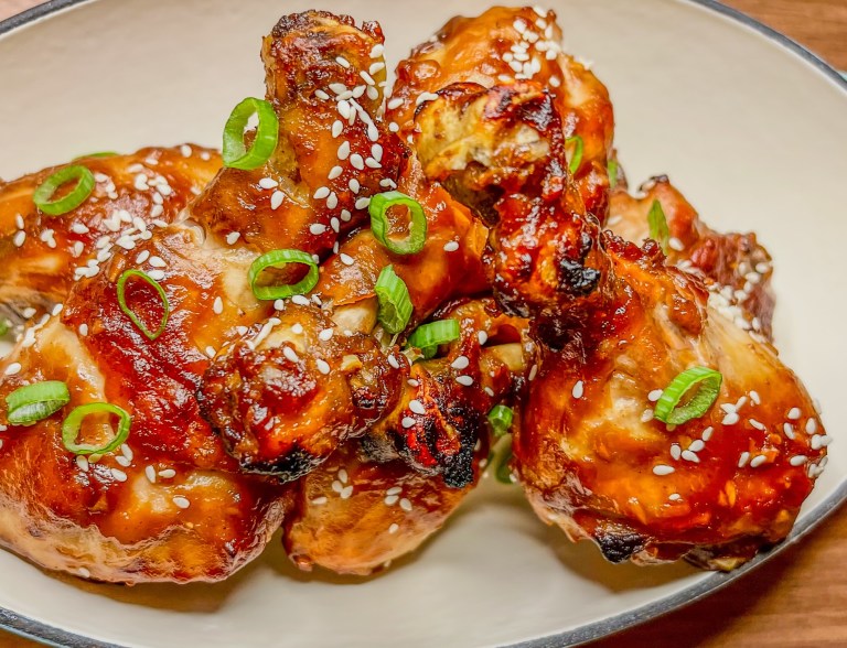 Asian Chicken Drumsticks in a glass dish on a wooden countertop