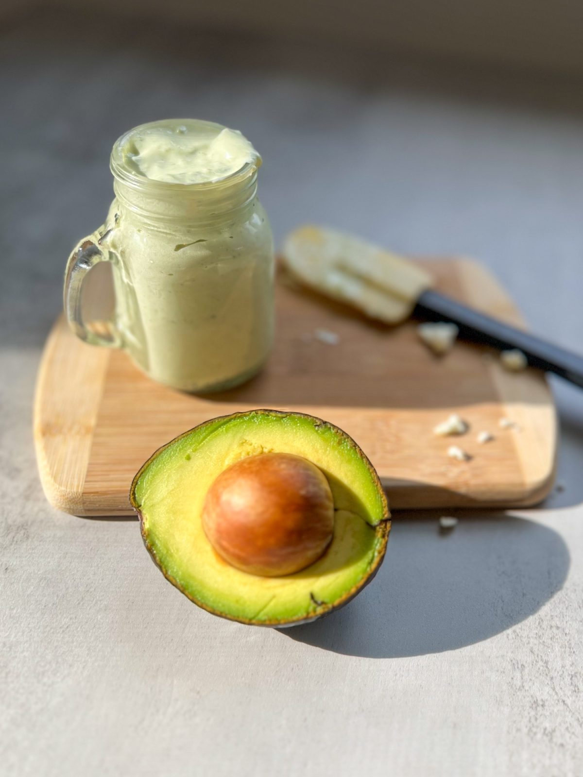 Avocado Blue Cheese Dressing in a glass dish with an avocado and rubber spatula nearby