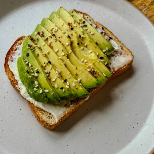 Avocado Toast on a white plate on a wooden table