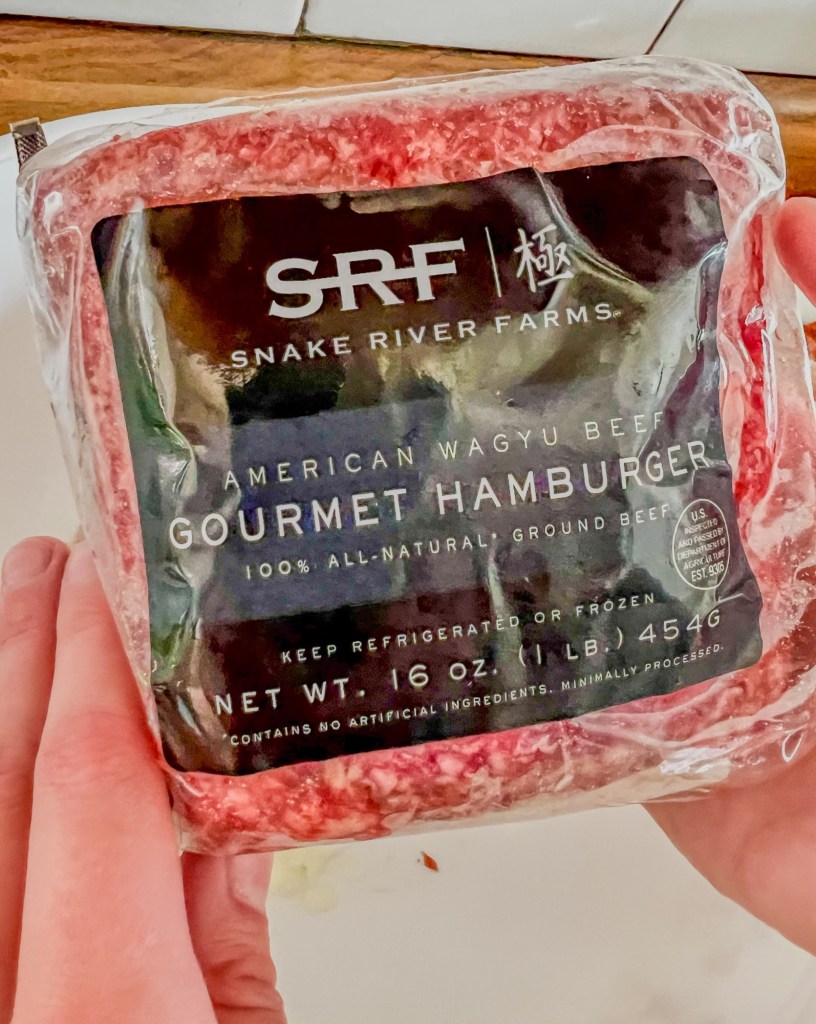 Snake River Farms wagyu beef brick being held up by some hands to show the label