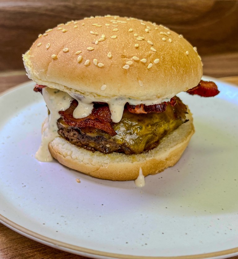 Bacon Cheeseburgers on a white plate on a wooden countertop