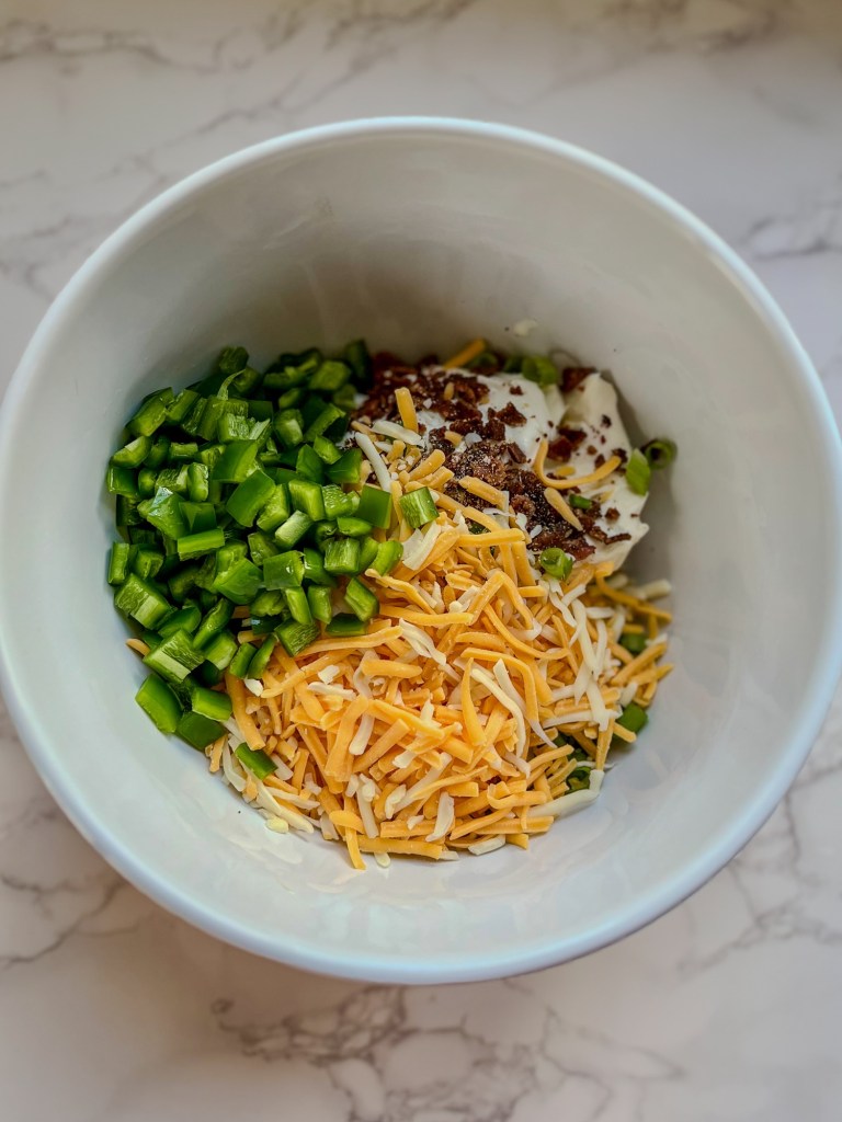 A bowl filled with ingredients for bacon jalapeño popper dip