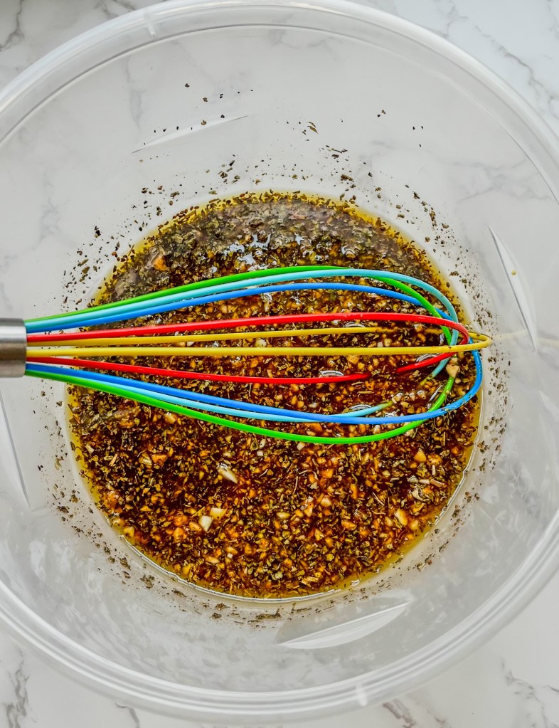 Balsamic chicken marinade in a large bowl with a whisk inside