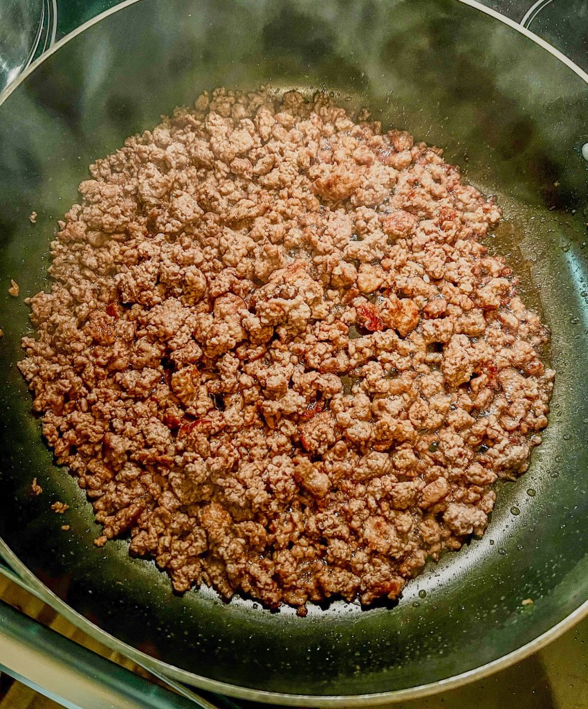 Ground beef browning in a skillet on the stove
