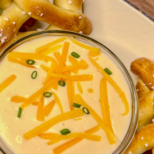 Beer cheese served with some pretzels in a serving dish on a wooden counter
