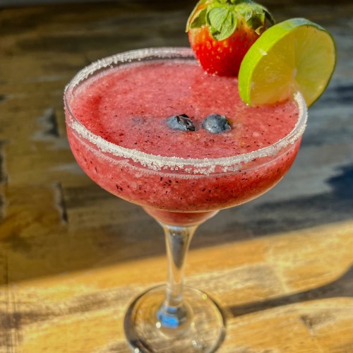 Berry Margarita with a lime and strawberry garnish on a table