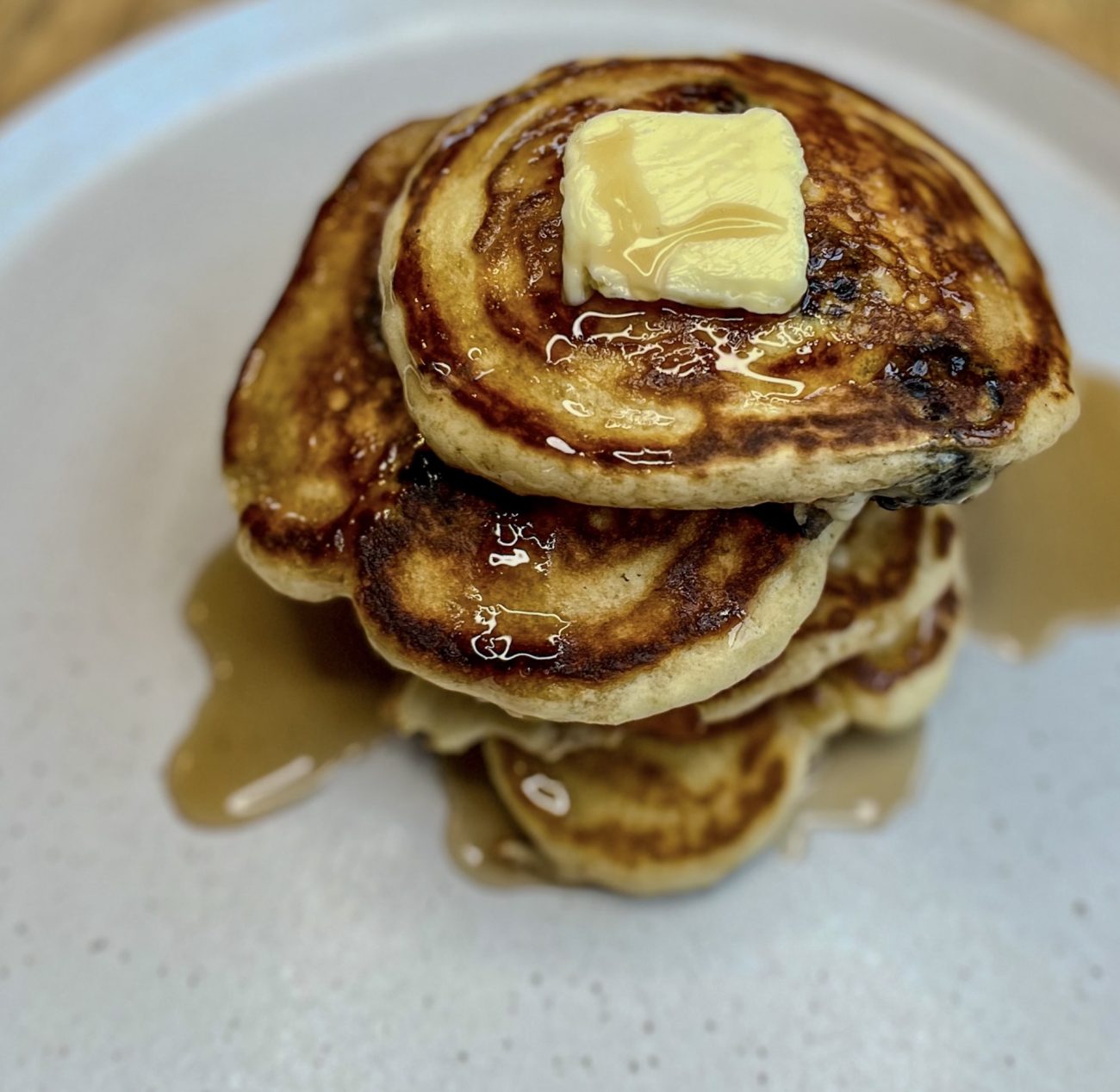 Blackberry pancakes on a white plate with butter and syrup on top
