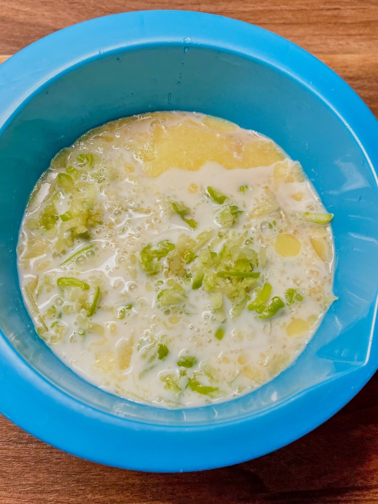 A blue bowl filled with wet ingredients to make caramel apple pancakes