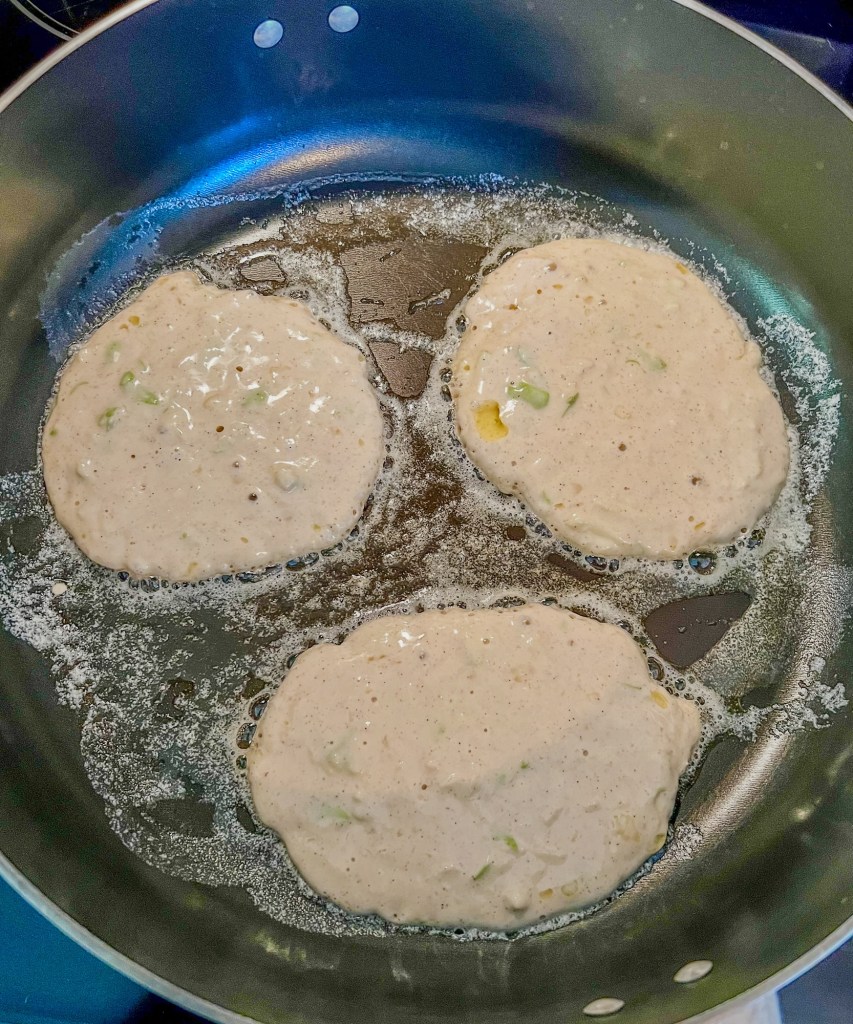 A large skillet with pancakes cooking inside