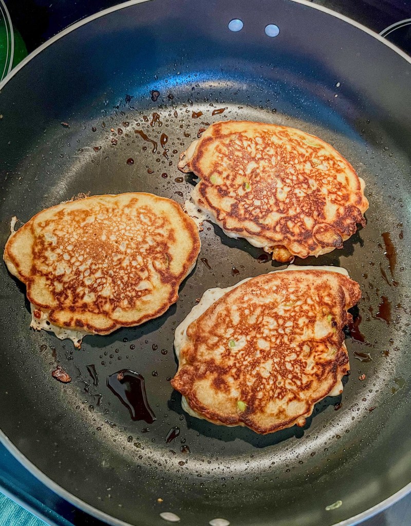 Caramel apple pancakes cooking in a skillet