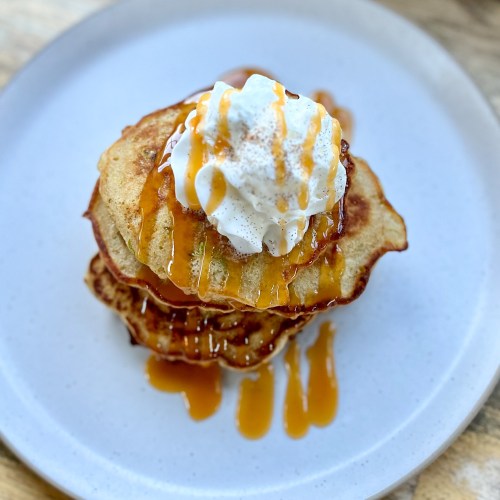 Caramel apple pancakes with caramel drizzled on top with whipped cream and cinnamon for garnish