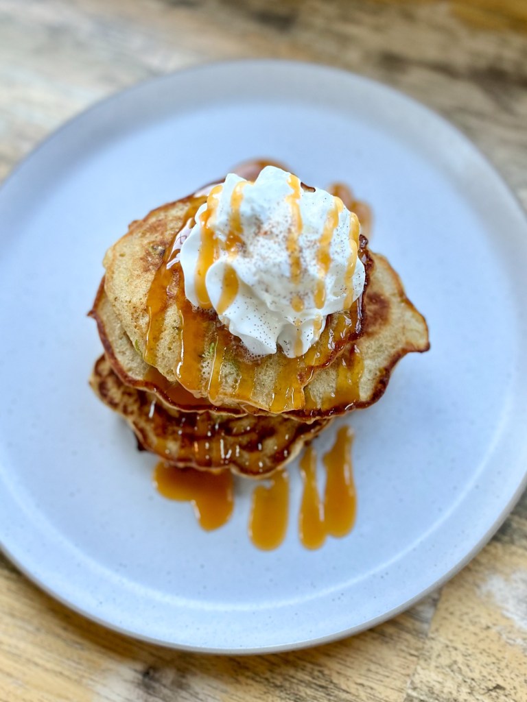 Caramel apple pancakes with caramel drizzled on top with whipped cream and cinnamon for garnish