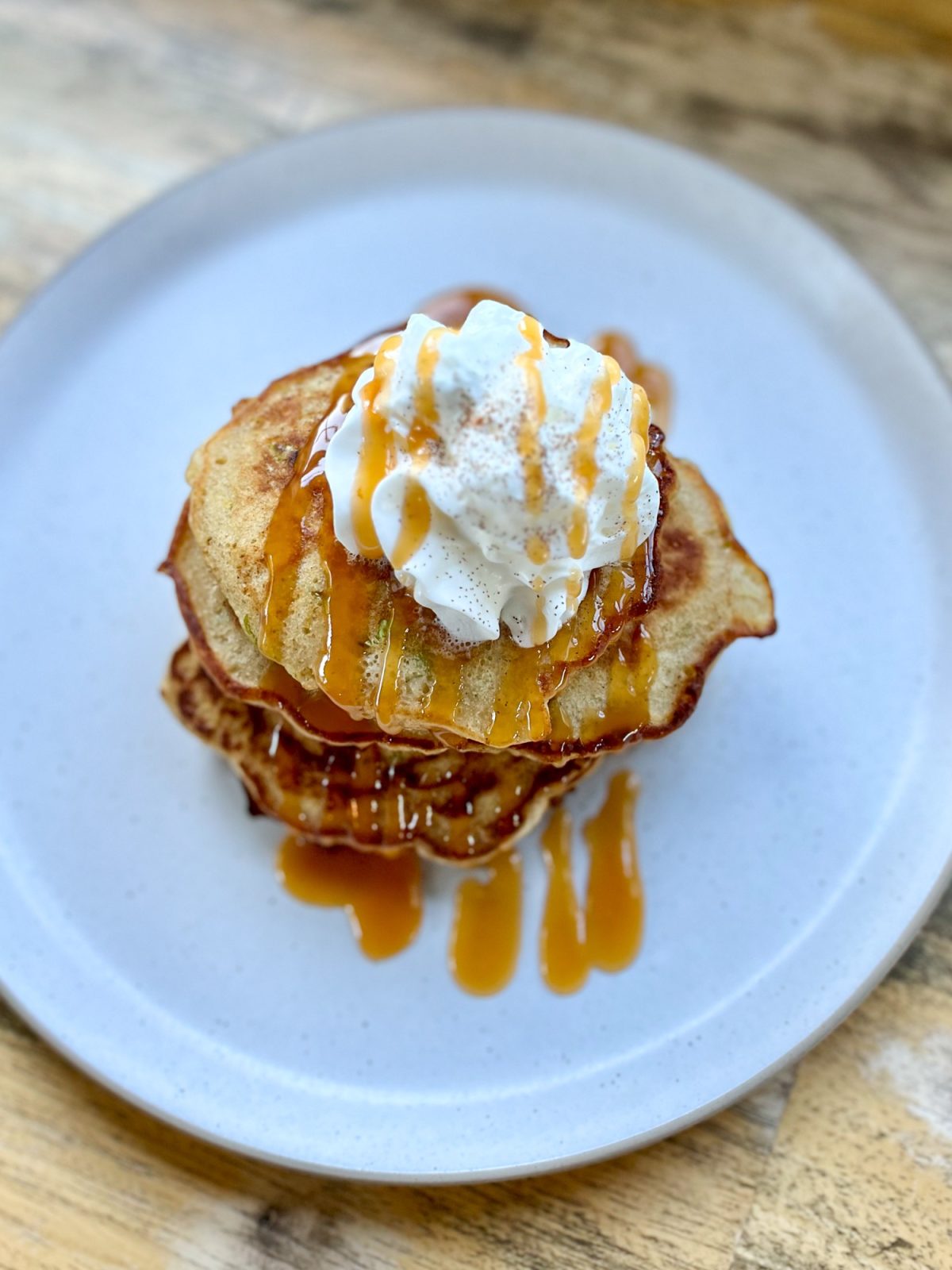 Caramel apple pancakes with caramel drizzled on top with whipped cream and cinnamon for garnish