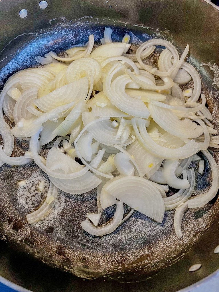 Sliced onions in a skillet with some butter and oil