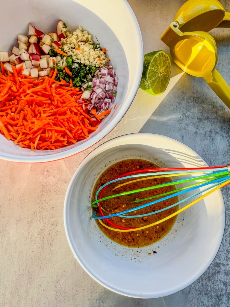 Carrot salad ingredients in a bowl with a honey citrus dressing ready to toss with it