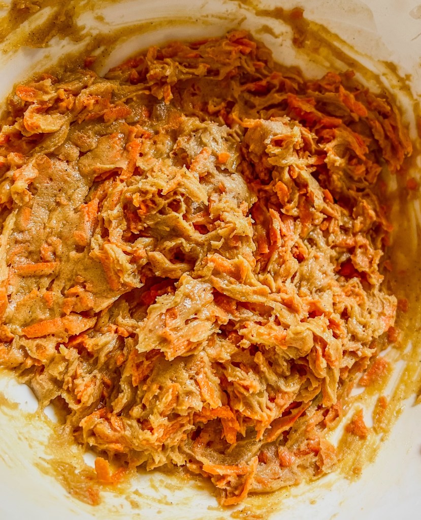 Wet and dry ingredients combined in a mixing bowl for carrot cake bars