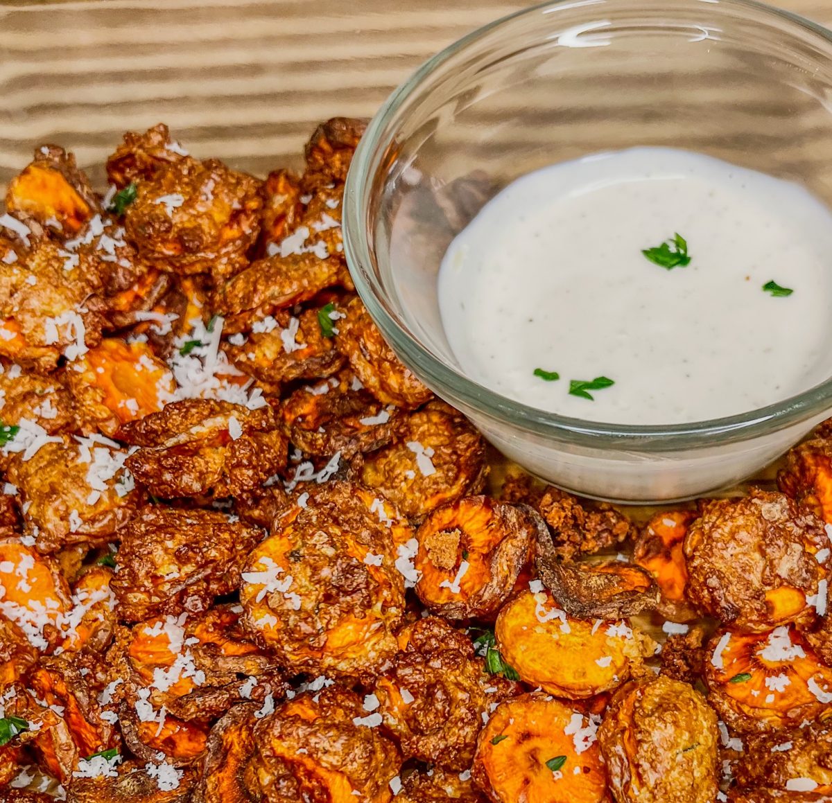 Carrot chips in a dish with some parmesan and parsley on top and ranch on the side