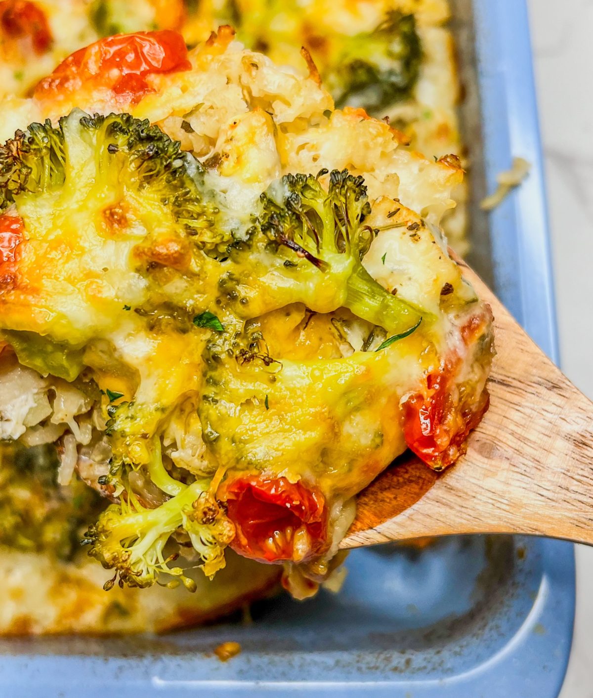 Cheesy broccoli chicken and rice fresh out of the oven in a pan, with a spoon scooping some out