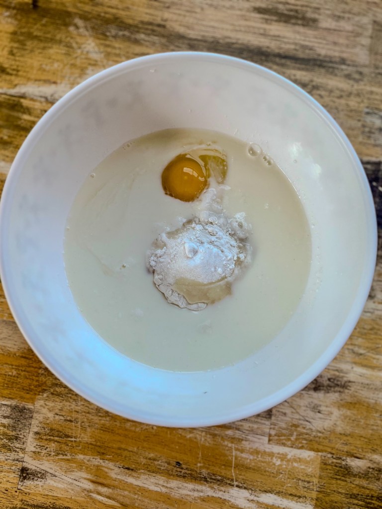 A mixing bowl filled with cobbler batter before being whisked