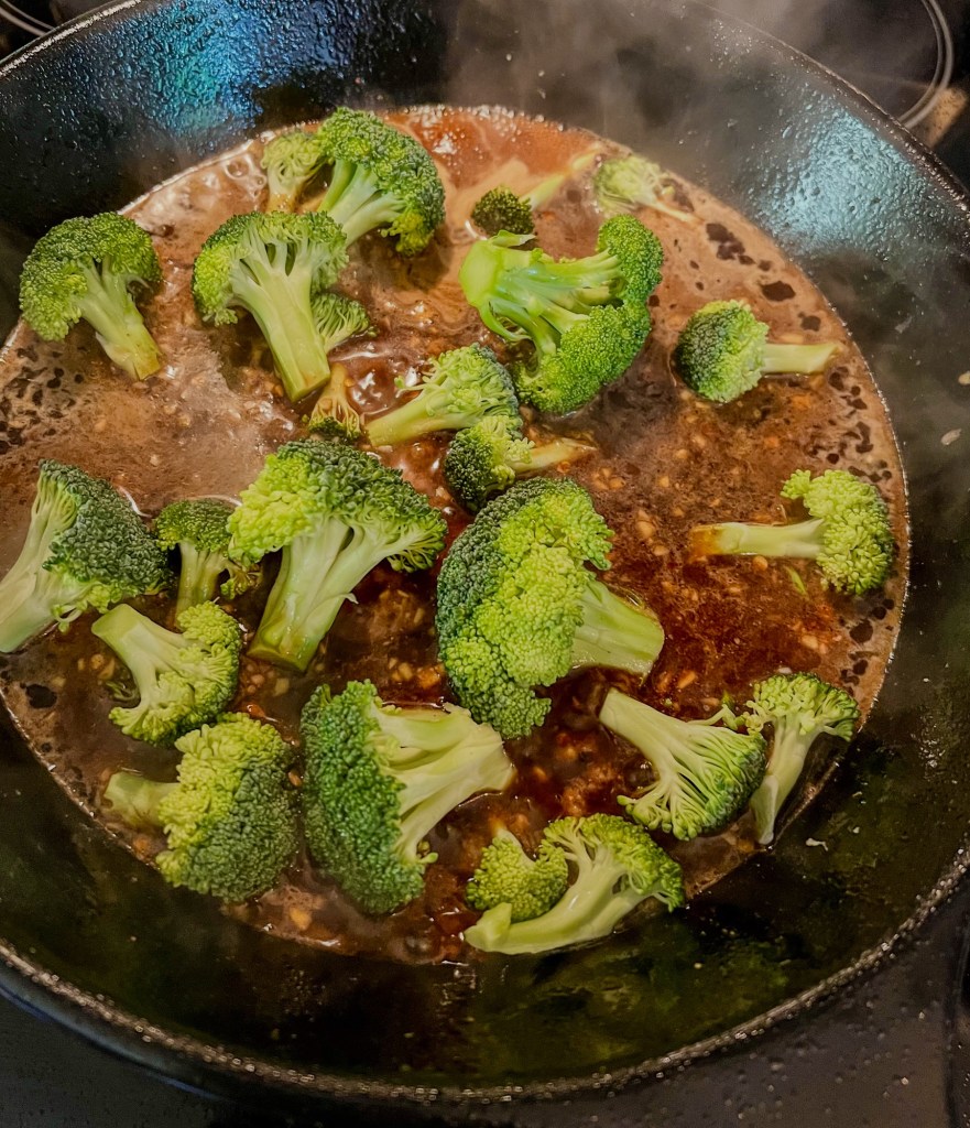 Broccoli and sauce cooking in a skillet on the stove