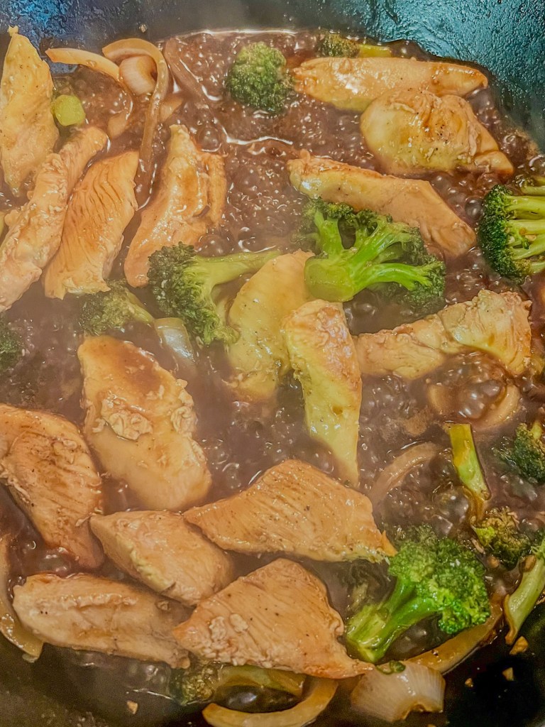 Chinese chicken and broccoli cooking in a skillet on the stove