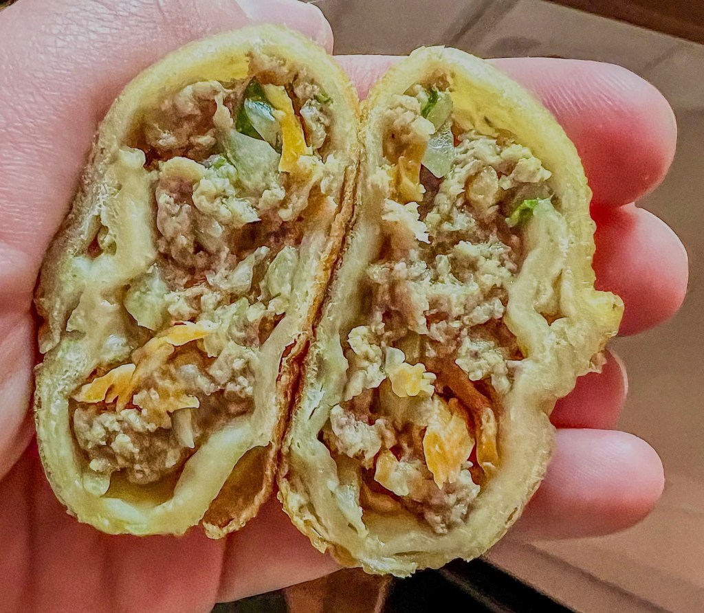 A chinese dumpling that's been cut in half to show the inside and a hand holding it up