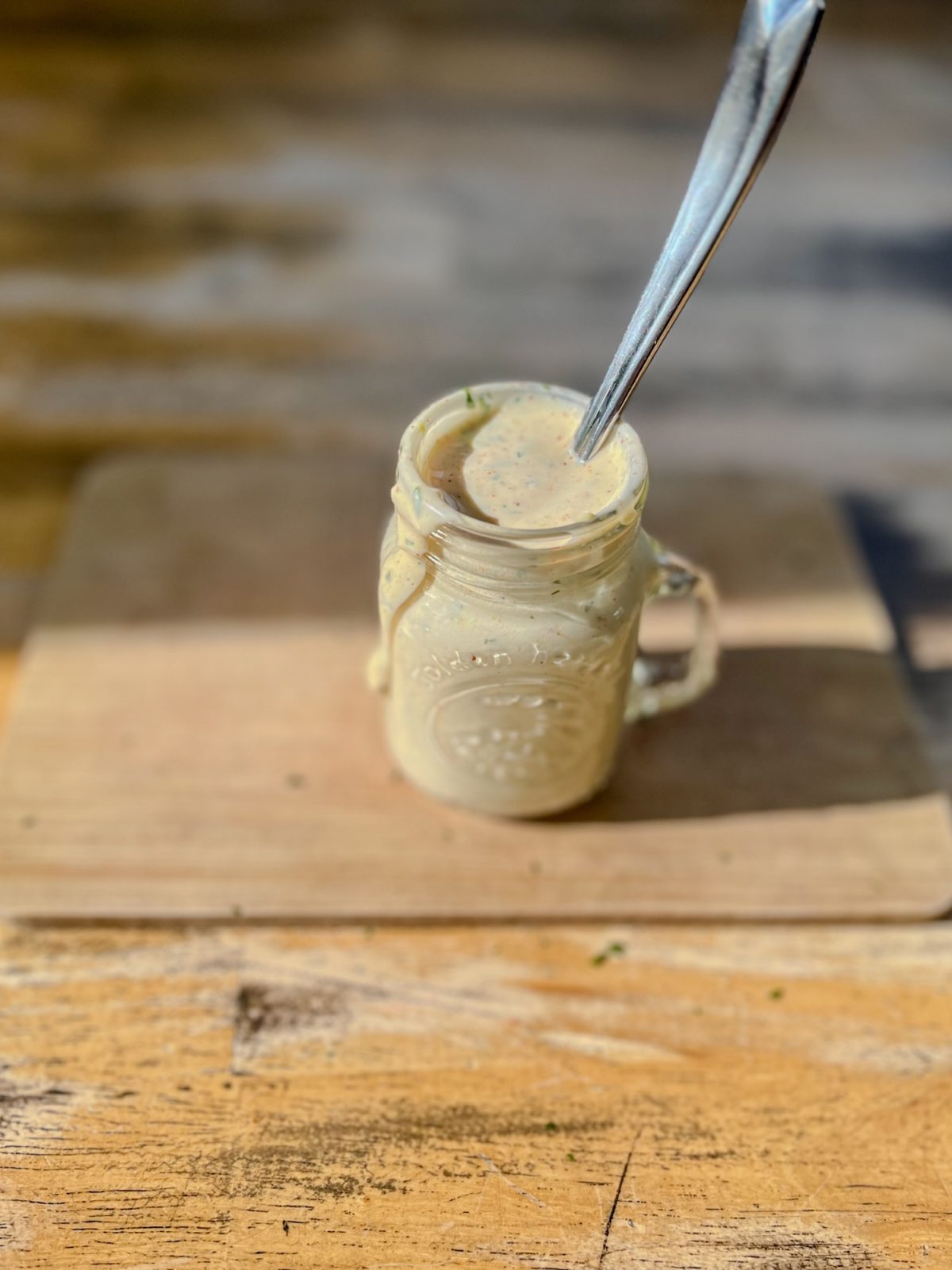 Chipotle Aioli in a mason jar with a spoon sticking out of it on a wooden table