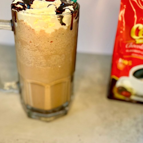 Chocolate Cherry Coffee Milkshake in a big mug with a bag of ground coffee next to it