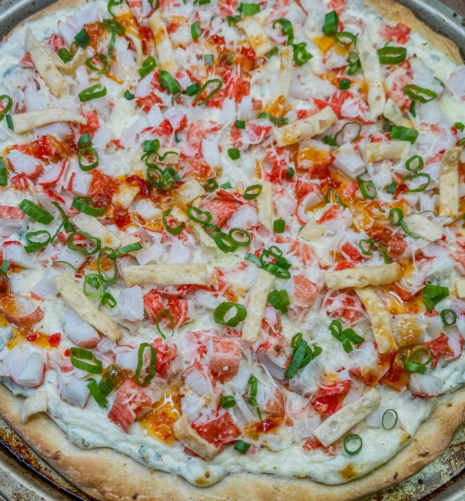 Crab rangoon pizza on a pan with some garnishes on top