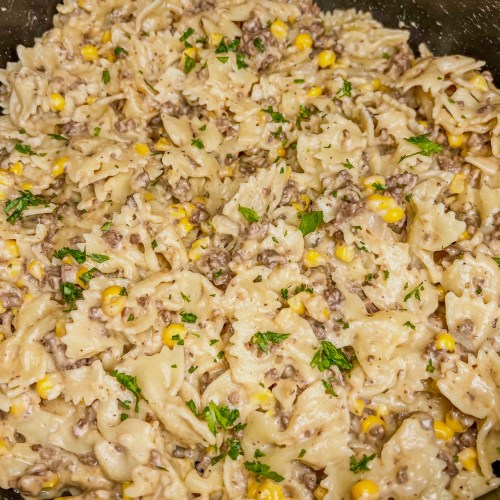 Creamy beef bowtie pasta in a skillet cooking on the stove