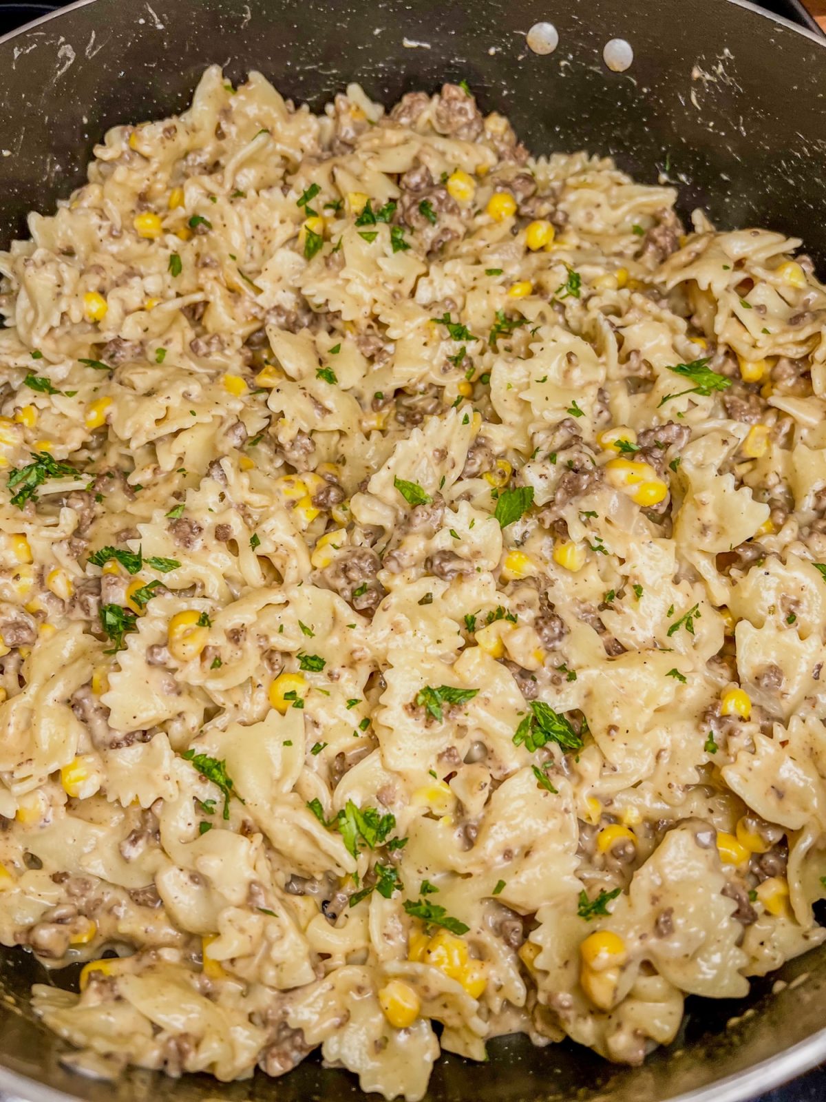Creamy beef bowtie pasta in a skillet cooking on the stove