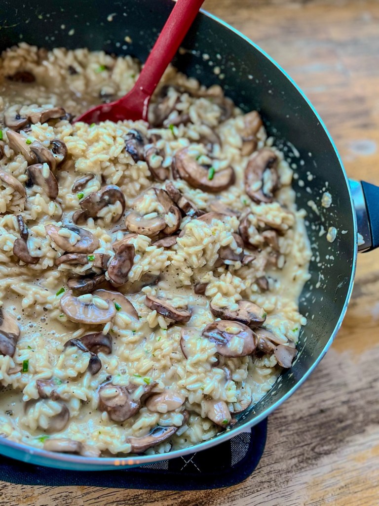 Creamy mushroom risotto in a skillet with a spatula sticking out