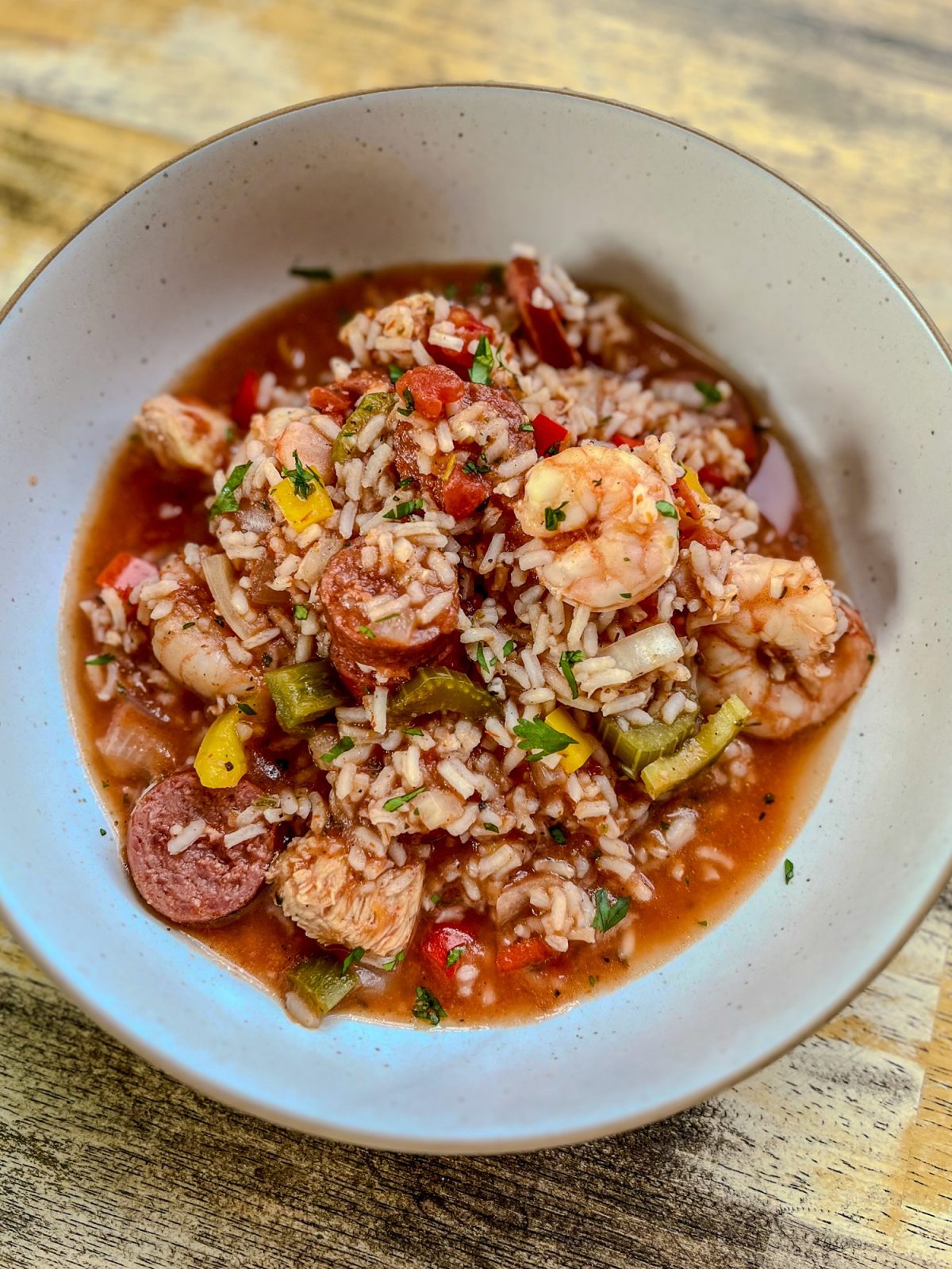 A white bowl filled with crockpot jambalaya on a wooden table