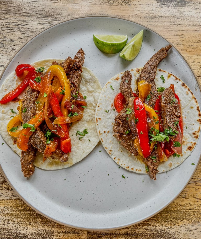 Flank Steak Fajitas on a white plate on a wooden table
