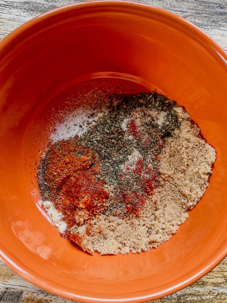 An orange bowl filled with spices for bbq ribs