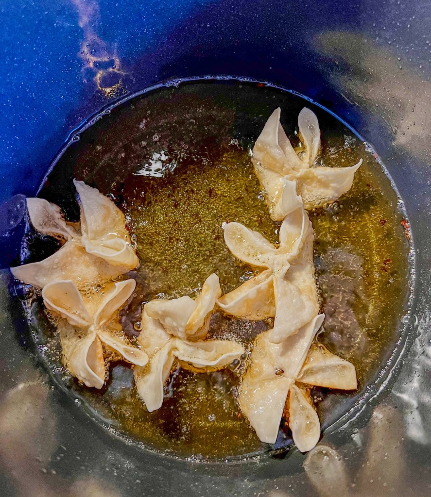 Crab rangoons frying in a pot