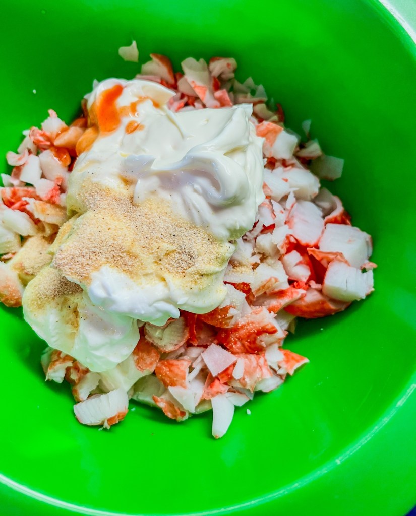 All the ingredients to make hot crab dip in a green bowl
