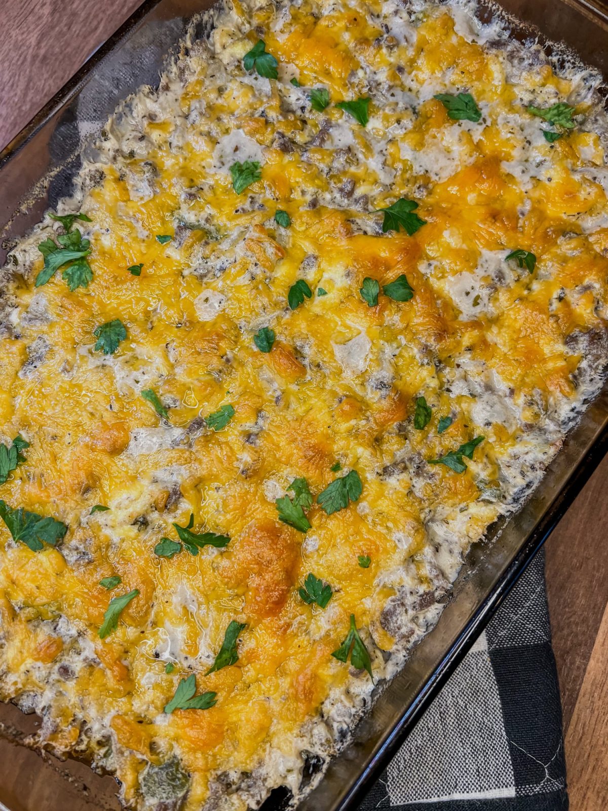 Beefy mushroom breakfast casserole in a baking dish with a hot pad underneath it