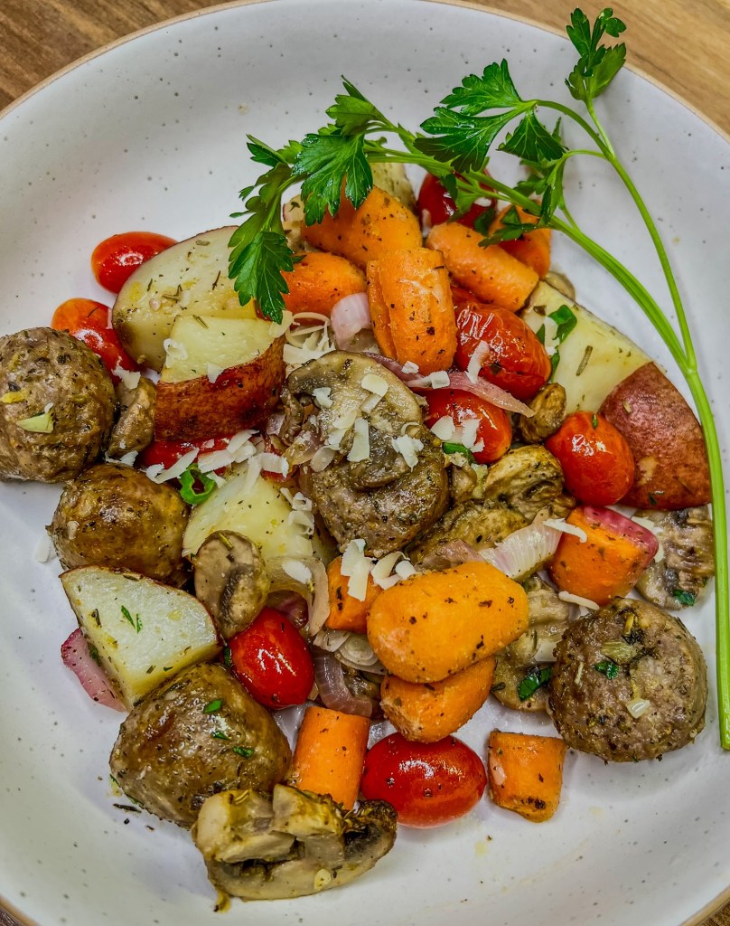 Sausage and potato sheet pan meal in a white bowl with parsley and parm for garnish