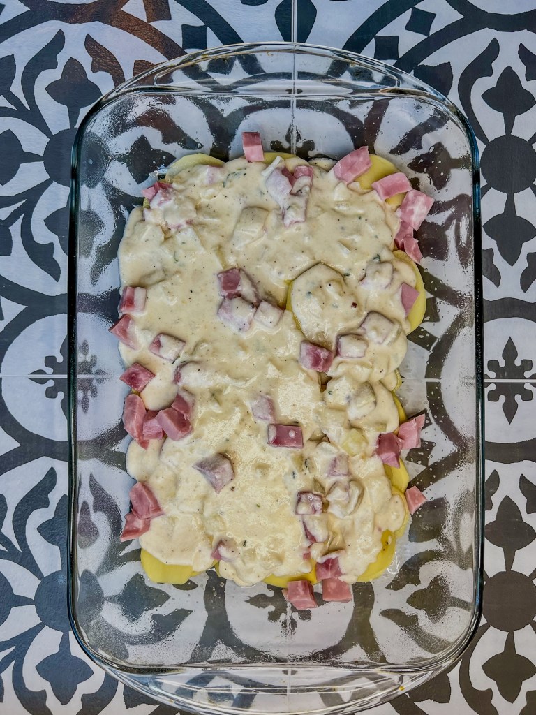 Potatoes, ham, and cheese sauce in a baking dish