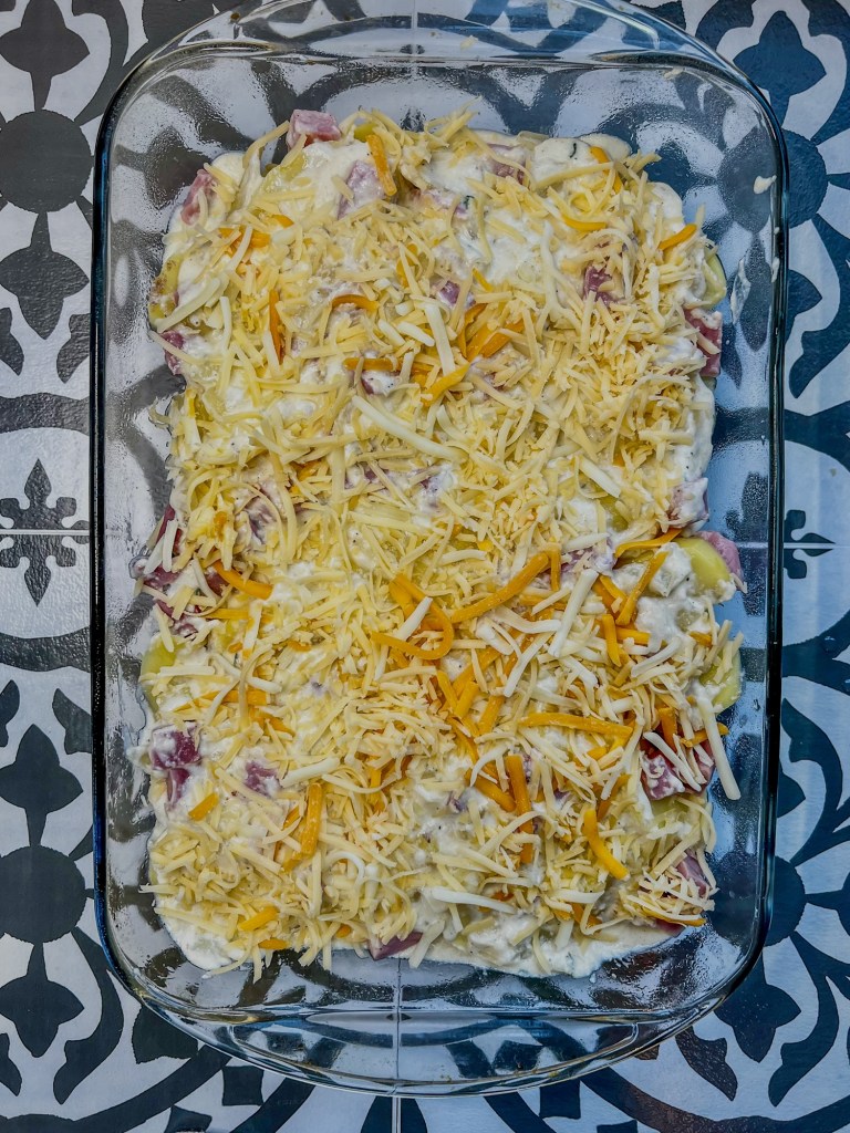 Ham and scalloped potatoes in a baking dish right before going into the oven