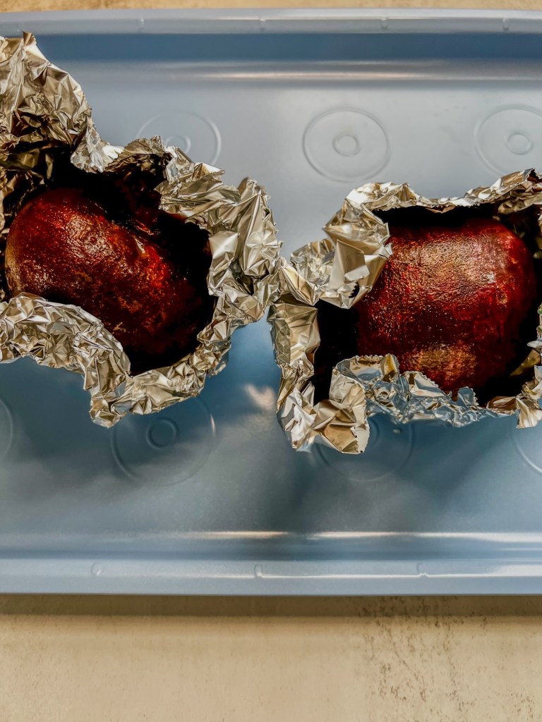 Beets in some foil on a baking sheet just before being roasted