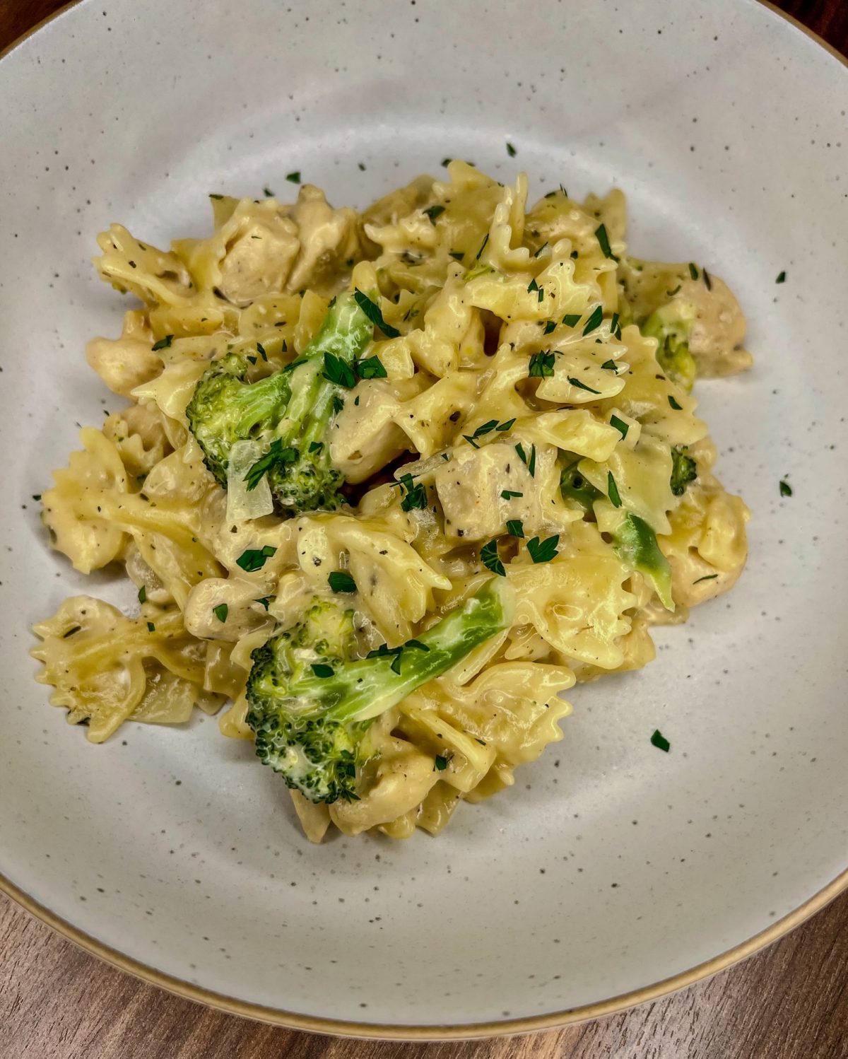 Cheddar Chicken Broccoli Bowtie in a white bowl on a wooden counter