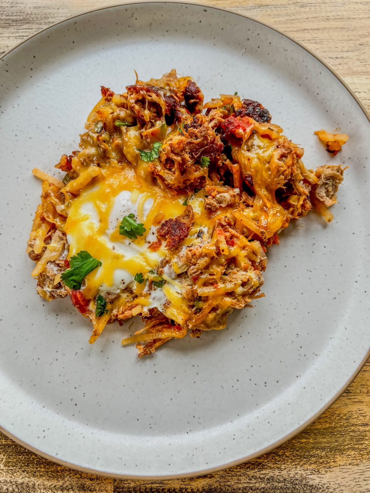 Pulled pork breakfast skillet on a white plate on a wooden table