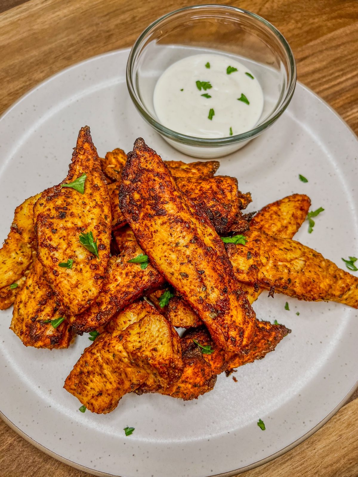 Air fryer chicken tenders on a white plate with a small dish of ranch next to it