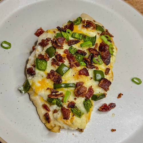 Jalapeño Popper Chicken on a white plate on a wooden counter