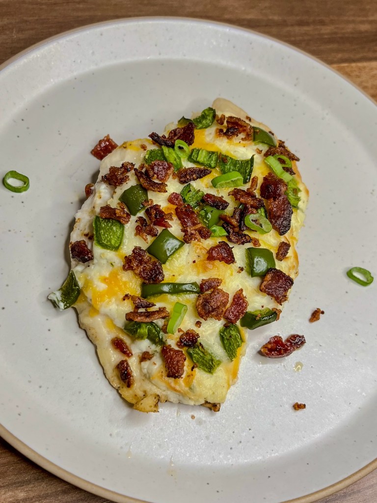 Jalapeño Popper Chicken on a white plate on a wooden counter