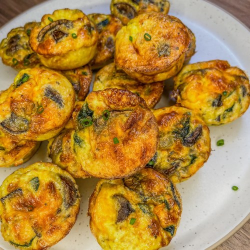 Mushroom Spinach egg cups on a white plate on a wooden countertop
